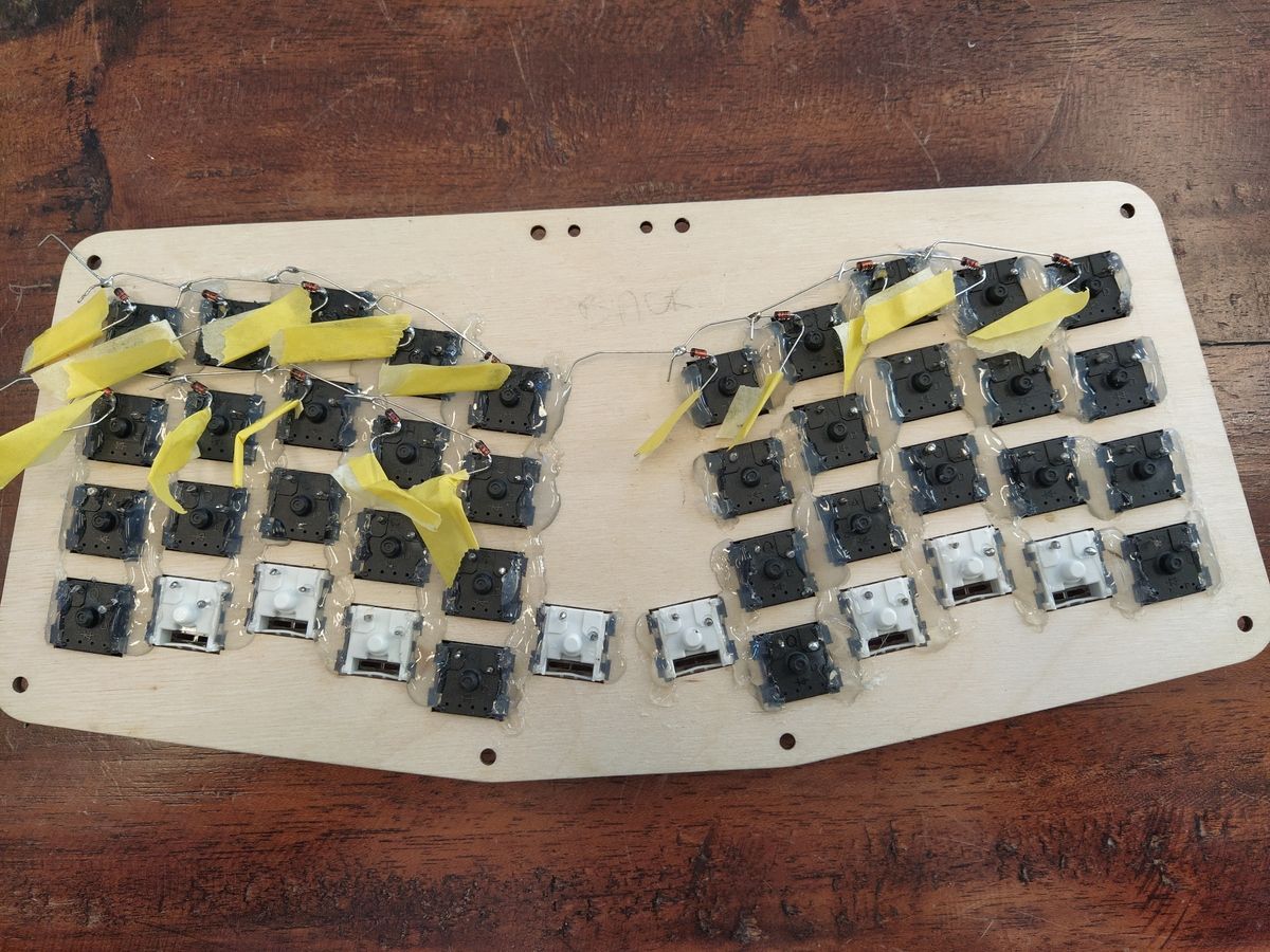 Red and black diodes soldered to the left pins of keyboard switches, connected in parallel row by row