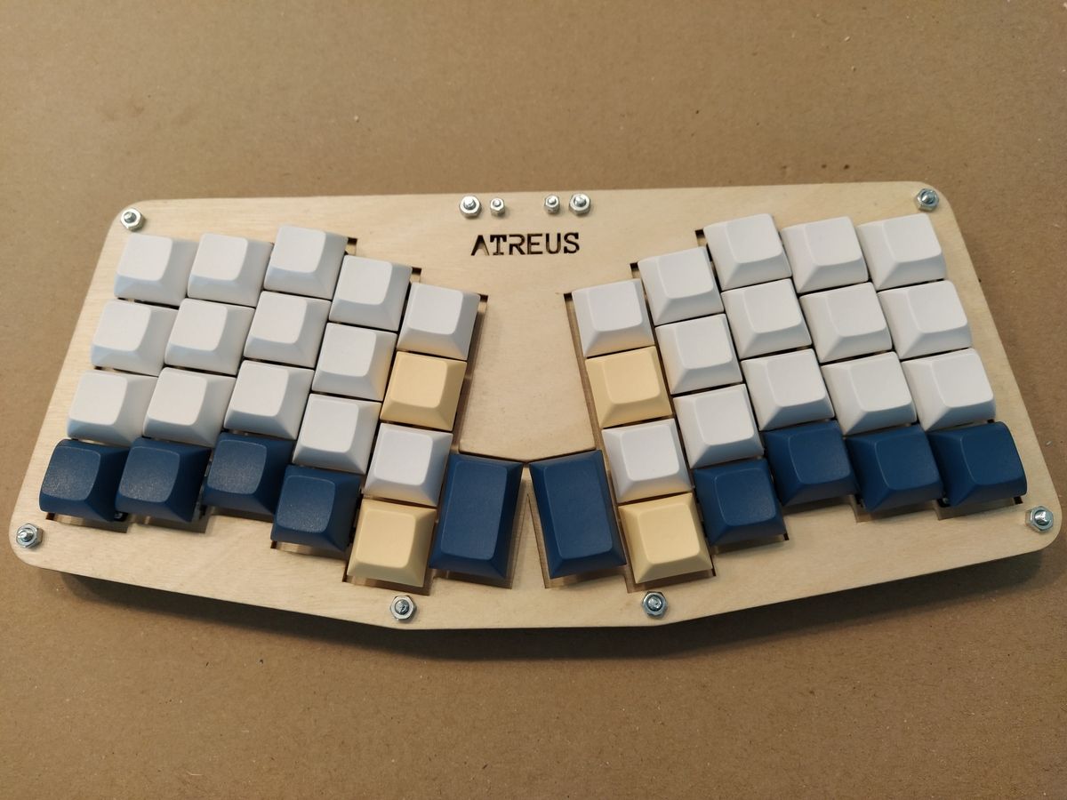 Fully assembled Atreus keyboard from above showing two-keyboard ergonomic layout with dark grey and beige keycaps on wooden case