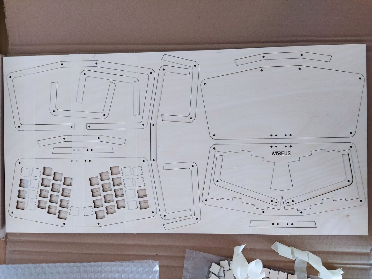 A light brown wooden plywood sheet, showing the laser-cut keyboard case components with charred edges from the cutting process.