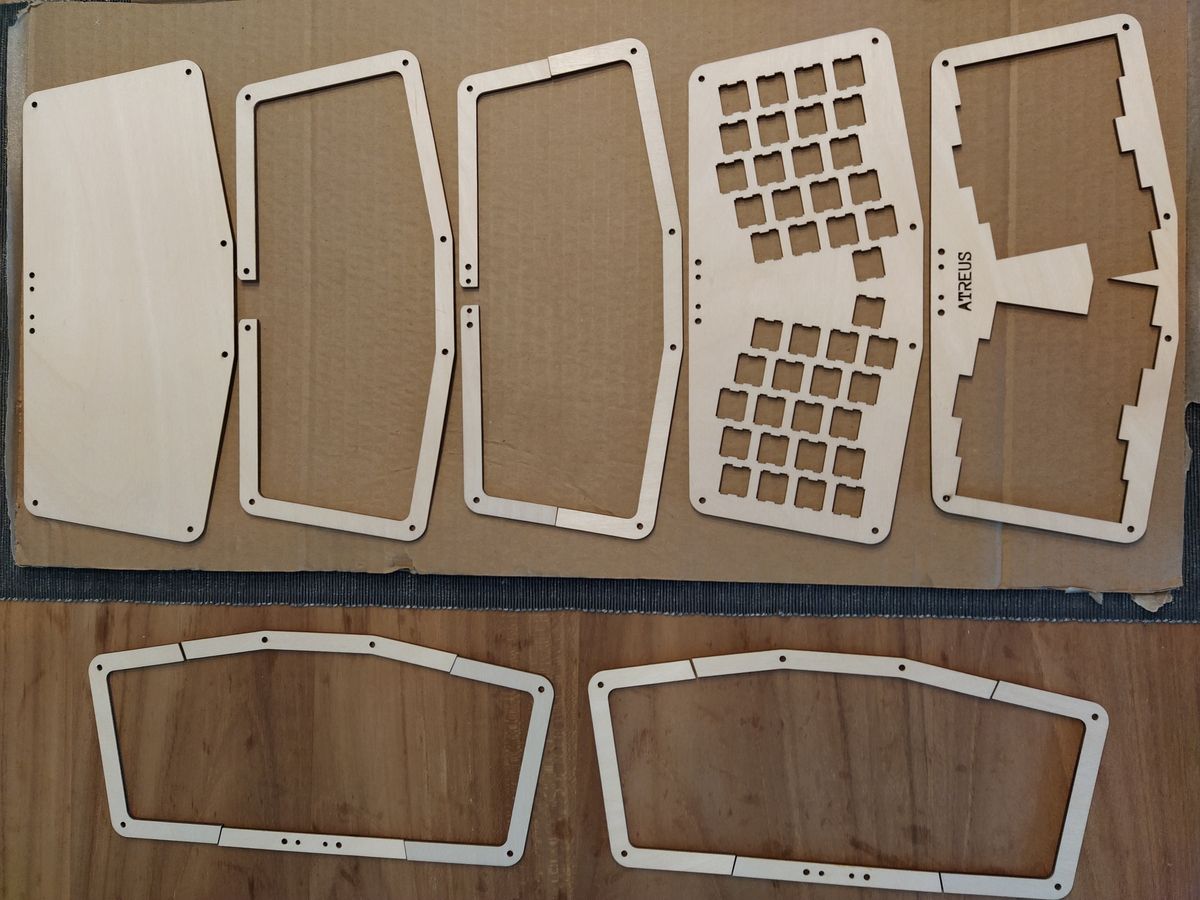 Scattered wooden keyboard case pieces with a shiny beeswax finish.