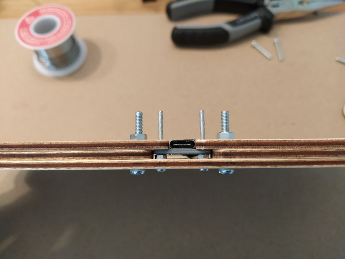 USB-C board and socket fitted inside wooden case with nuts holding layers