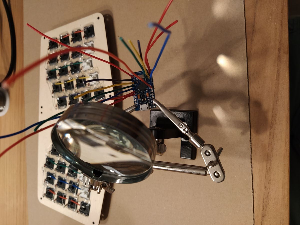 Colored wires soldered to the microcontroller, held with a soldering iron 'third-hand'