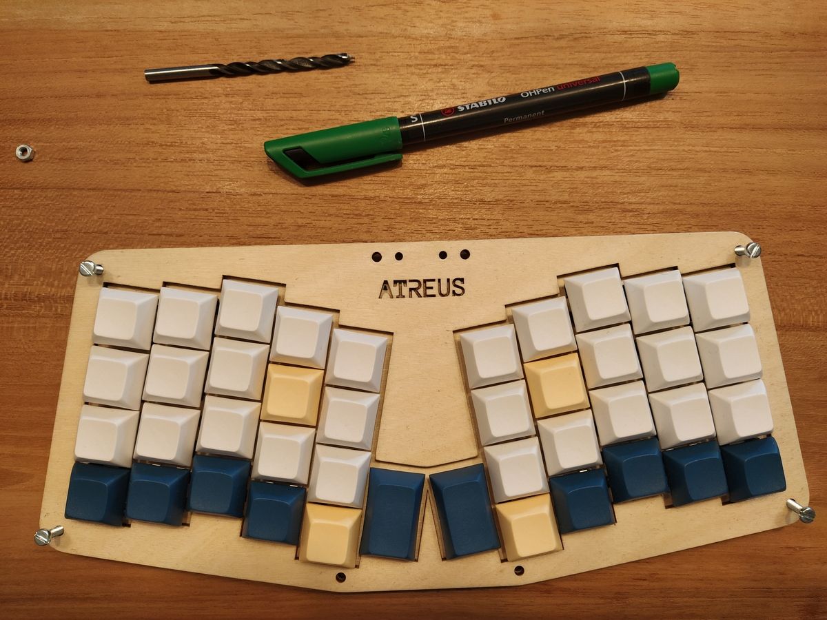Assembled Atreus keyboard with a green dot marking indicating where to drill, inside the A of Atreus.