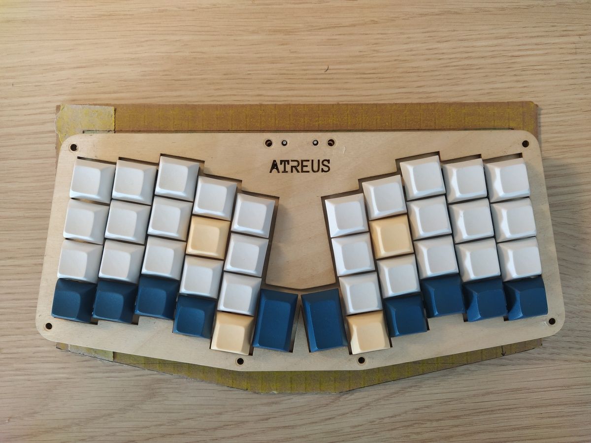 An Atreus keyboard case positioned on top of brown cardboard template showing the housing outline.